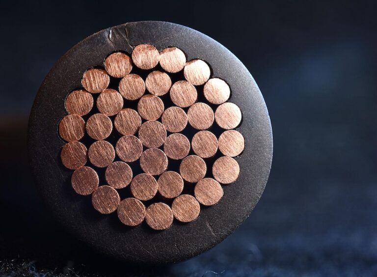 Close-up of the cross-section of a thick electrical cable, showing multiple copper wires bundled together inside black insulation—ideal for lightning protection or to install a lightning rod system safely.